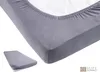 A close-up view of a grey fitted sheet on a mattress, with a smaller folded sheet in the bottom left corner. Produktbild-Vorschau
