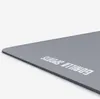 A close-up, angled view of a gray yoga mat with the brand name printed on it. Produktbild-Vorschau