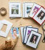 A collection of picture frames and photos arranged on a wooden surface, with an orange cat interacting with one of the photos. Produktbild-Vorschau