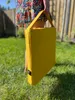 A person holding a yellow heated seat cushion outdoors. Náhled obrázku produktu