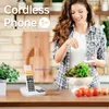 A woman is preparing food in a kitchen while a cordless phone sits on the counter. Produktbild-Vorschau