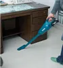A person is using a cordless vacuum cleaner to clean the floor under a desk. Podgląd zdjęcia produktu