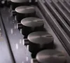A close-up, angled view of several metallic knobs on a dark surface, likely a control panel. Voir les images du produit