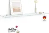 A glass shelf mounted on a white wall, decorated with a framed picture, a vase with a flower, and a stone. Produktbild-Vorschau