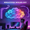 A person is sitting at a desk in front of a computer, with a colorful cloud-shaped LED light and neon lights on the wall behind them. Produktbild-Vorschau