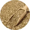 A close-up shot of dried mate tea leaves being scooped with a wooden spoon. Voir les images du produit