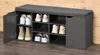 A shoe cabinet with a cushioned top, showing various shoes stored inside. The cabinet has multiple compartments and a closed door on the left side. Náhled obrázku produktu