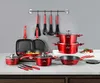 A collection of red cookware and kitchen utensils displayed on a countertop against a gray wall. Produktbild-Vorschau