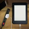 A black power strip with a white plug and a white e-reader charging on a wooden surface, with black pencils in the upper left corner. Voir les images du produit