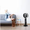 A young woman is lying on a couch with her legs up, looking at her phone, while a fan stands in the background next to a small table with a lamp and a cup. Produktbild-Vorschau