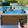A woman relaxing in a hot tub next to a swimming pool in an outdoor setting. Produktbild-Vorschau