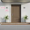 A wooden door with two wall lamps mounted on the wall next to it, and two potted plants on the steps in front of the door. Produktbild-Vorschau