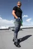 A man stands on a rooftop wearing work pants and boots. Náhled obrázku produktu
