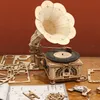 A wooden model of a classical gramophone is displayed on a wooden surface with scattered parts and instructions. Podgląd zdjęcia produktu