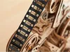 A close-up shot of a wooden model film projector, focusing on the film reel and gears. Produktbild-Vorschau