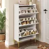 A white shoe cabinet with gold legs is shown in a hallway next to a door and a potted plant. Anteprima dell’immagine prodotto