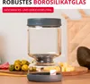 A glass jar with a gray lid and base, placed on a wooden surface with food items in the background. Anteprima dell’immagine prodotto