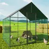A chicken coop with chickens in a grassy field with hay bales in the background. Náhled obrázku produktu