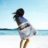A person stands on a beach, wrapped in a blanket with a VW van print. Anteprima dell’immagine prodotto
