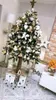 A decorated Christmas tree stands in a room with gifts underneath and other festive decorations. Podgląd zdjęcia produktu