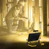 A construction worker is kneeling and working on wiring in a building under construction, illuminated by a work light. Náhľad obrázku produktu