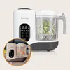 A white and gray multifunctional baby food maker with a transparent container showing broccoli being steamed. Produktbild-Vorschau