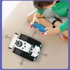 A child is playing with a remote-controlled robot made of building blocks, using a smartphone to control it. Náhled obrázku produktu