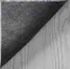 The underside of a rug is shown, with its anti-slip texture and stitched edge visible. The rug is placed on a light-colored wooden surface. Produktbild-Vorschau