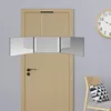 A tri-fold mirror with LED lights is mounted on a wooden door. A chair with a patterned pillow is visible to the right, and a clock is on the wall. Produktbild-Vorschau