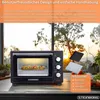 A mini oven is shown on a countertop in front of a window with a sunset view. Accessories are displayed next to it. Podgląd zdjęcia produktu