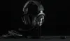 A black Logitech G PRO X gaming headset is displayed on a black stand against a black background. A pair of earcups are placed in the foreground. Náhled obrázku produktu
