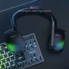 A gaming headset and keyboard are shown on a dark surface, with the headset displaying RGB lighting. Náhled obrázku produktu