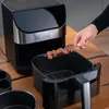 A hand is placing a skewer of meat into an air fryer basket. Podgląd zdjęcia produktu