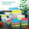 A collection of clear plastic food storage containers with colorful lids, arranged in stacks and groups, with some vegetables in the foreground and a plant in the background. Produktbild-Vorschau