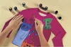 Hands painting a t-shirt with cats and flowers using fabric paints. Produktbild-Vorschau