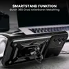 A black smartphone case with a ring stand is shown in a close-up, angled view, with a laptop and headphones blurred in the background. Produktbild-Vorschau