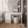 A bedroom scene featuring a white high-gloss dressing table with drawers, a stool, and a laptop. Produktbild-Vorschau