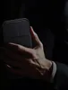 A person's hand holding a black smartphone case. Náhled obrázku produktu