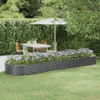 A raised garden bed filled with purple flowers sits in a garden setting with a table and chairs under an umbrella in the background. Náhľad obrázku produktu