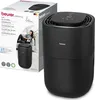 A product shot of a black air humidifier next to its packaging box, which features an image of a woman using the humidifier. Voir les images du produit