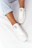 A person's legs wearing white sneakers and jeans, shown from the knees down. Podgląd zdjęcia produktu