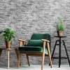 A living room scene with a chair, side table, and plant against a brick wallpaper. Produktbild-Vorschau
