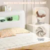A close-up view of a bed with a white upholstered headboard featuring integrated LED lighting and shelf compartments. Decorative pillows and bedding are visible. Produktbild-Vorschau