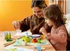 A woman and a child are playing a board game together at a table. Anteprima dell’immagine prodotto