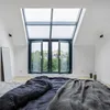 A bedroom with a large skylight window and a bed with dark bedding. Produktbild-Vorschau
