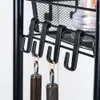 A close-up view of black metal hooks on a shelf unit, with two utensils hanging from the hooks. Náhled obrázku produktu