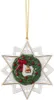 A white star-shaped ornament with a green wreath, red berries, a red bow, and a gold bell in the center, hanging from a gold chain. Náhľad obrázku produktu