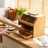 A person is taking bread out of a wooden bread box on a kitchen counter. Produktbild-Vorschau