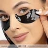 A close-up of a woman's face with black under-eye patches applied. Náhľad obrázku produktu