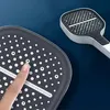 Nahaufnahme eines grauen und weißen Duschkopfs mit einem Finger, der eine der Düsen drückt Náhľad obrázku produktu